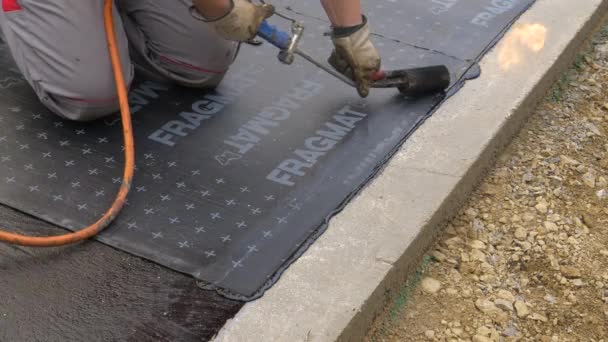 CLOSE UP: Contractor uses a blowtorch to burn a bitumen sheet to the ground. — Stock Video