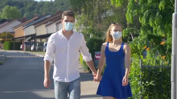 CLOSE UP: Paar küsst sich während des Spaziergangs mit schützenden Gesichtsmasken — Stockvideo
