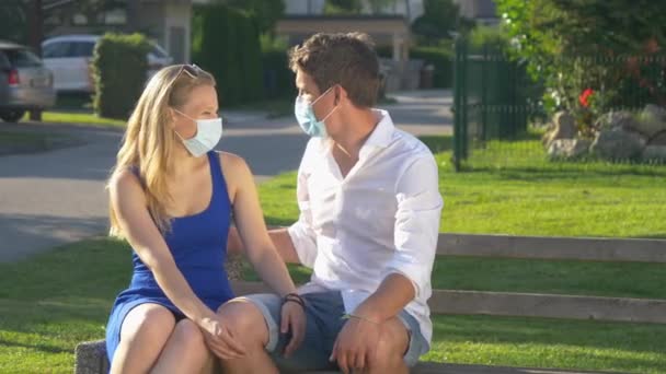 CLOSE UP: Maskiertes Paar flirtet und küsst sich auf Parkbank. — Stockvideo