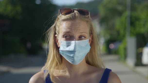 PORTRAIT: Funny shot of woman biting off piece of wafer through hole in facemask — Stock Video