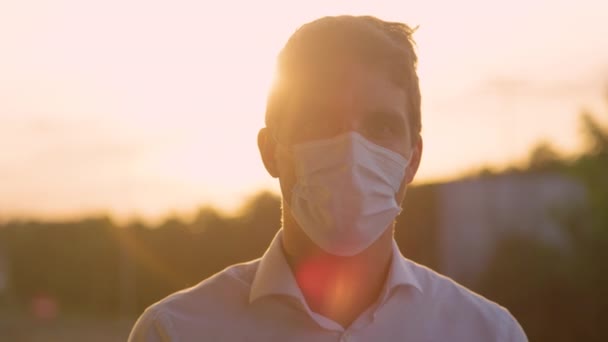 PORTRAIT Anak muda tersenyum di bawah nya facemask pelindung selama pandemi covid-19 — Stok Video