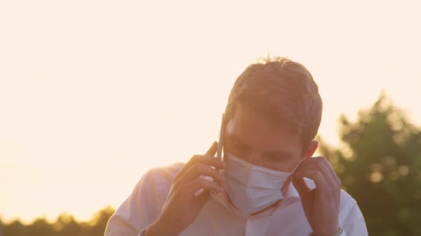 CERRAR, DOF: Hombre irritado se quita la mascarilla mientras habla por teléfono. — Vídeos de Stock