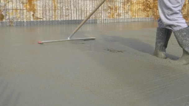 LOW ANGLE: Onherkenbare werknemer gebruikt een nivelleringstool om het natte beton te verspreiden — Stockvideo