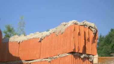 Tuğla ustası bir sıra tuğlanın üzerine havan topu saçmak için bir spatula kullanır..