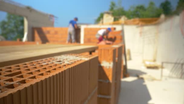 ZAMKNIJ, DOF: Niewyraźne ujęcie wykonawców układających cegły i budujących ściany. — Wideo stockowe
