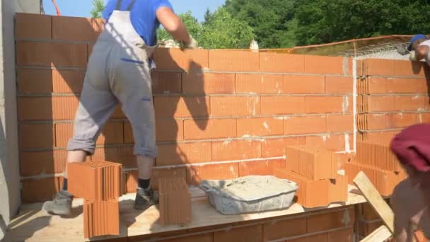 CERRAR: Constructores ponen ladrillos para construir paredes dentro de la casa en construcción. — Vídeo de stock