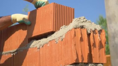 Tanımlanamayan inşaatçı, duvarın tepesine yeni bir tuğla seriyor..