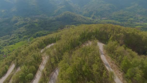 AERIAL: Fotografía cinematográfica de una carretera de recambio terminando una colina cubierta de bosque. — Vídeo de stock