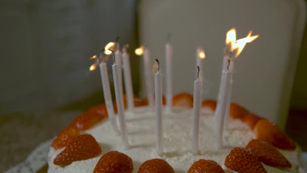 Las velas en la parte superior del pastel de coco y fresa son sopladas por una persona desconocida. — Vídeo de stock
