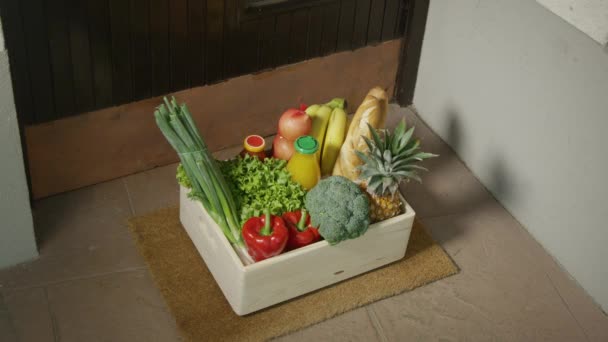 ZAMKNIJ SIĘ: Starsza pani podnosi pudełko pełne organicznych artykułów spożywczych na wycieraczce. — Wideo stockowe