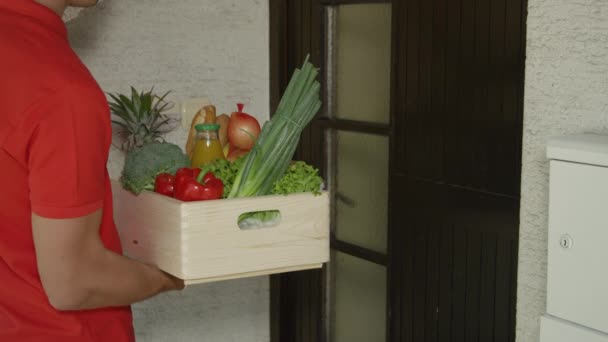 CHIUSURA: L'uomo di consegna irriconoscibile consegna una scatola di generi alimentari alla donna sorridente. — Video Stock