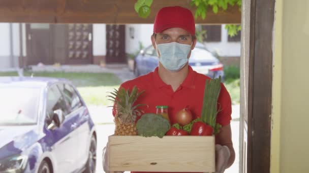 PORTRAIT: Vrolijke man levert een doos met verse boodschappen voor de deur. — Stockvideo