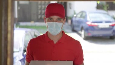 Yaşlı kadın pizzasını teslim ederken maske takan kuryeye kapıyı açıyor.