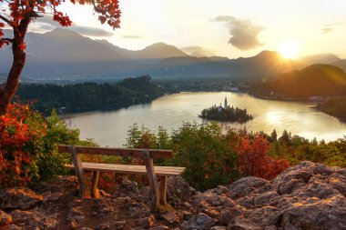 Gün batımını gösteren, göle bakan boş bankı aydınlatan nefes kesici bir çekim.
