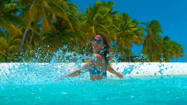 CERRAR: Chica alegre en bikini salpicando el agua turquesa con las manos. — Foto de Stock