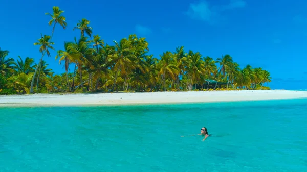 DRONE: Viajante feliz nadando ao longo da pitoresca praia de areia branca. — Fotografia de Stock
