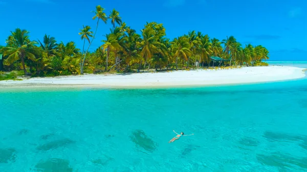 AERIALE: Ragazza spensierata in vacanza nuotando sulla schiena vicino all'isola tropicale. — Foto Stock