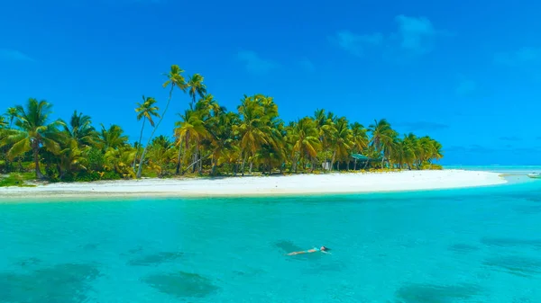 DRONE: Vrouwelijke reiziger ontspannen door te zweven op het oppervlak van turquoise oceaan. — Stockfoto