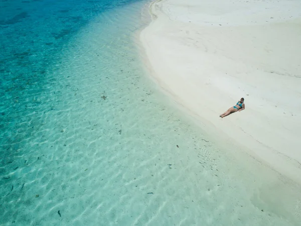 AERIAL: Chica en bikini tumbada en la playa de arena y bronceado en las Islas Cook. —  Fotos de Stock