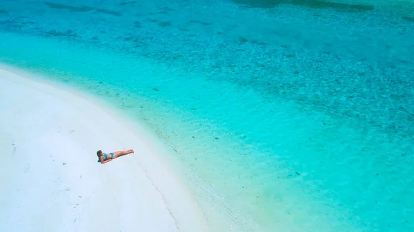 DRONE: volando sopra la turista in bikini sdraiata sulla spiaggia e prendendo il sole. — Foto Stock