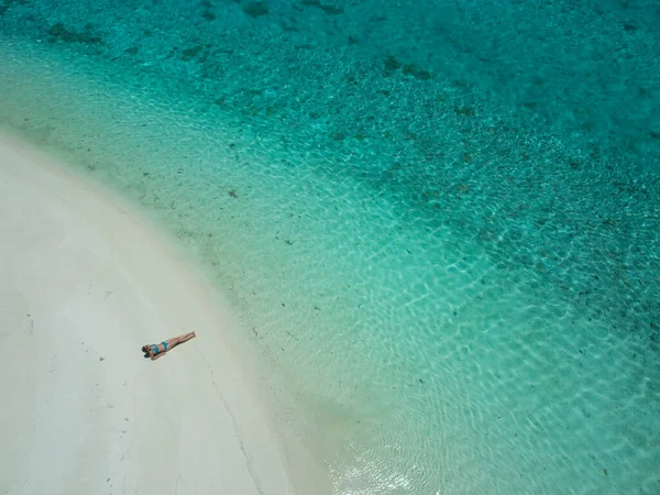 AERIAL: Femeie tânără întinsă pe plajă și plajă lângă oceanul turcoaz . — Fotografie, imagine de stoc