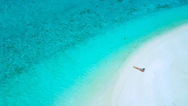 AERIAL: Zborul deasupra suntanning-ului turistic feminin pe plaja tropicală goală . — Fotografie, imagine de stoc