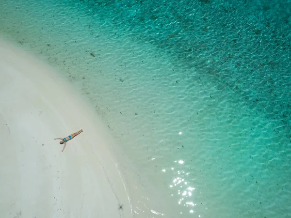 TOP DOWN: Beztroska kobieta leżąca na piaszczystej plaży z wyciągniętymi ramionami. — Zdjęcie stockowe