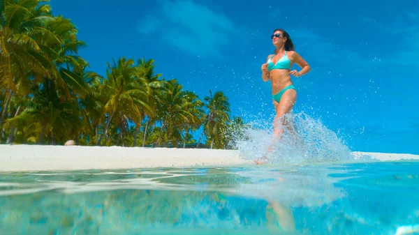 BEJELENTKEZÉS: fiatal turista nő élvezi a nyaralást, miközben fut végig a strandon. — Stock Fotó