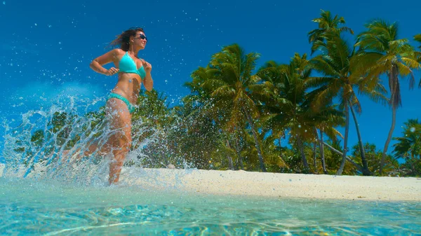 Üveges óceán víz fröcsköl körül lány fut végig egzotikus strand. — Stock Fotó