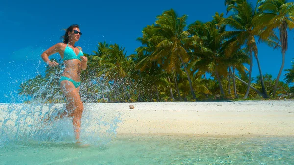 LOW ANGLE: gyönyörű gondtalan női utazó fut le festői trópusi strand. — Stock Fotó