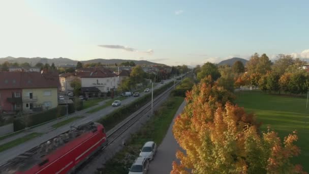 AERIAL: Industriezug transportiert im Herbst Fracht an einem Vorstadtviertel vorbei — Stockvideo