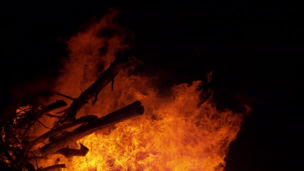 CLOSE UP: Cinematic shot van vurige vlammen overspoelen een grote stapel brandhout. — Stockvideo