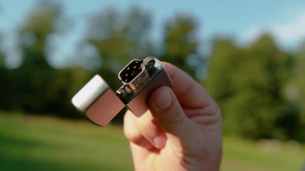 CERRAR: Hombre irreconocible hábilmente golpea el encendedor de metal abierto durante el picnic. — Vídeo de stock