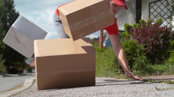 CLOSE UP: Людина з незграбною доставкою падає на землю і скидає картонні коробки — стокове відео
