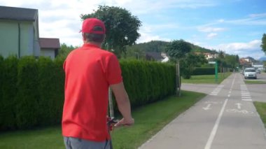 Teslimatçı iki paketle birlikte kaldırımdan aşağı elektrikli scooter sürüyor.