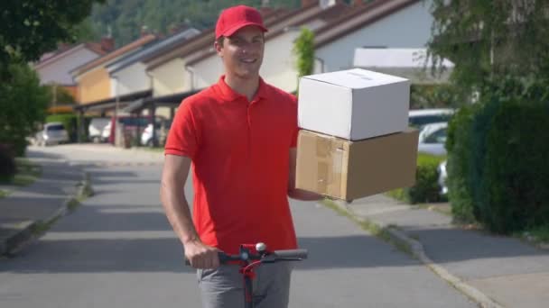 CLOSE UP: Roekeloze koerier druppels twee pakketten tijdens het rijden op een elektrische scooter. — Stockvideo