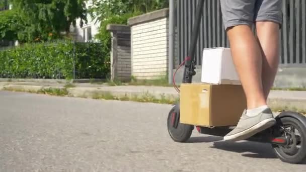 低角度：无法辨认的信使用电子摩托车运送两个纸板箱. — 图库视频影像