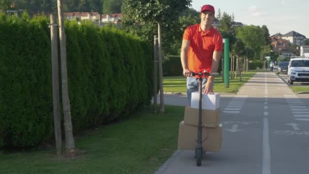 SLOW MOTION: Kurier fährt E-Scooter bei Paketzustellung in Vorstädten — Stockvideo