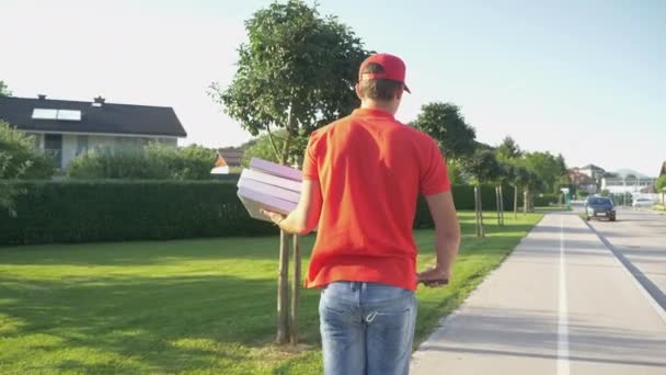CLOSE UP: kurir yang tidak dikenal mengantarkan pizza di pinggiran kota pada e-scooter. — Stok Video