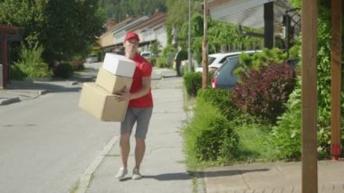 Tembel genç teslimatçı güneşli bir günde birinin garaj yoluna paket atıyor..