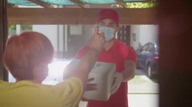 Yaklaşın. Endişeli kadın, kuryenin paket getirmesini engellemek için dezenfektan kullanıyor.