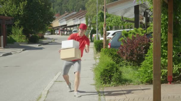 SLOW MOTION Rude courier making his round around the suburbs kicks three parcels — Stock Video