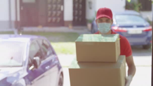 Ritratto: corriere allegro arriva alla porta d'ingresso e solleva un pacco. — Video Stock