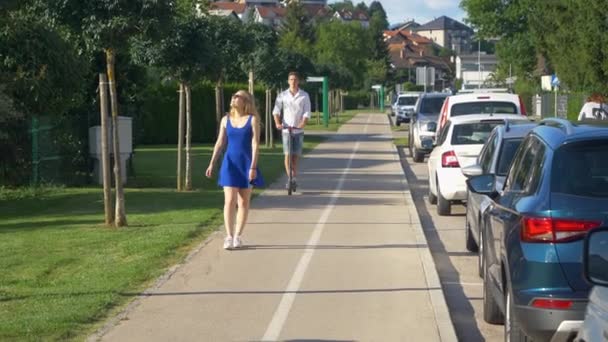 CLOSE UP: Woman gets angry at guy swerving past her on his electric scooter. — Stock Video