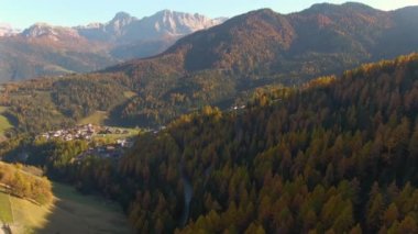 Sonbahar renkli Dolomitlerle çevrili küçük bir kasabaya doğru uçuyorlar..