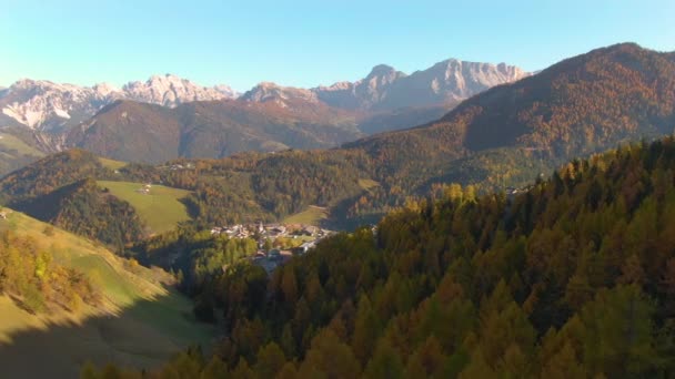 DRONE: Flying towards a small town surrounded by autumn colored Dolomites. — Stock Video
