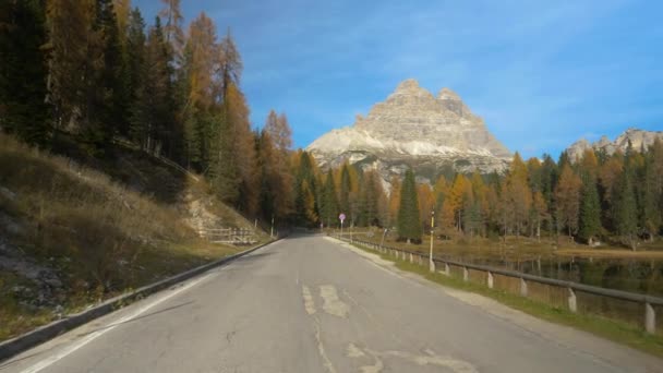 Scatto cinematografico di una strada asfaltata vuota che scorre vicino al lago Antorno in autunno. — Video Stock