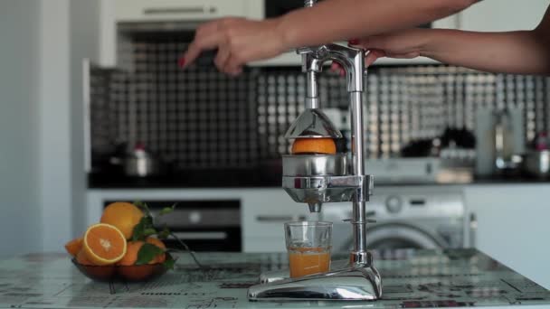 Woman hands squeeze fresh orange juice in a juicer — Stock Video