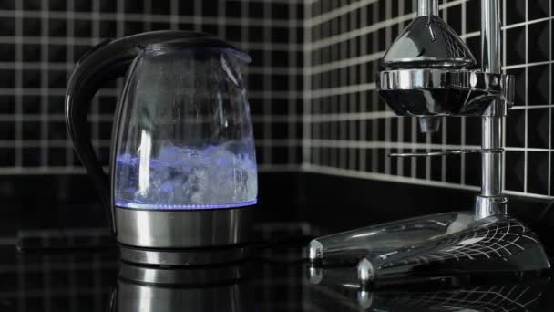 Waterkoker met blauw hoogtepunt is koken. De hand van de vrouw neemt uit theepot — Stockvideo