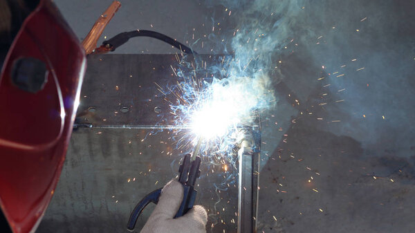 Flash from electric welding. Man in a protective mask from light